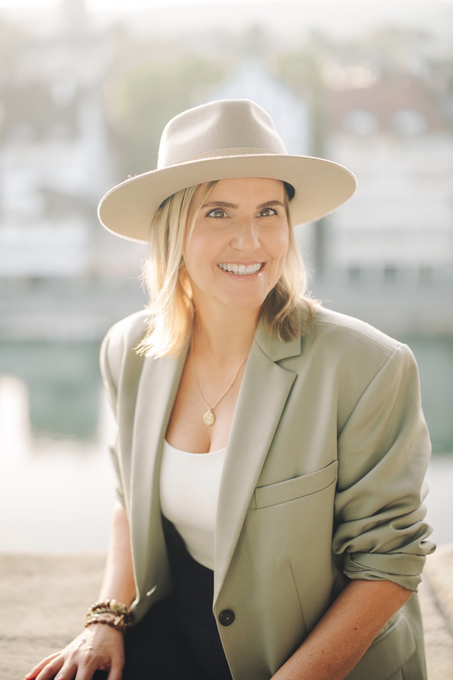 Woman wearing a beige hat and light green blazer with a blurred background
