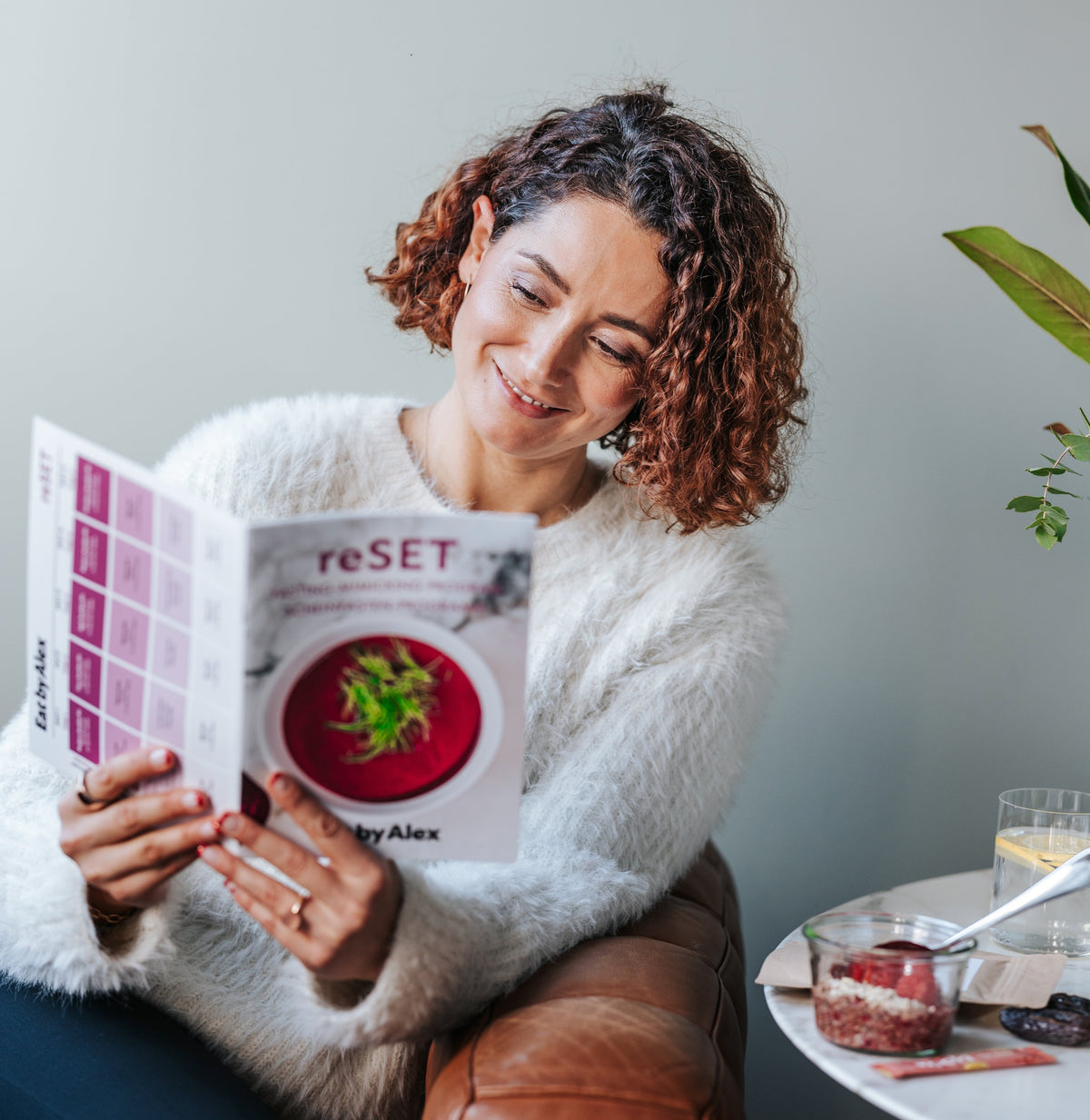 Woman reading a book titled 'RESET' in a cozy indoor setting.